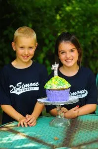 A birthday cake with a number seven candle in front of two children
